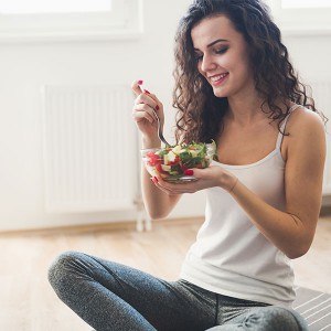 Una giovane ragazza mangia un'insalata 